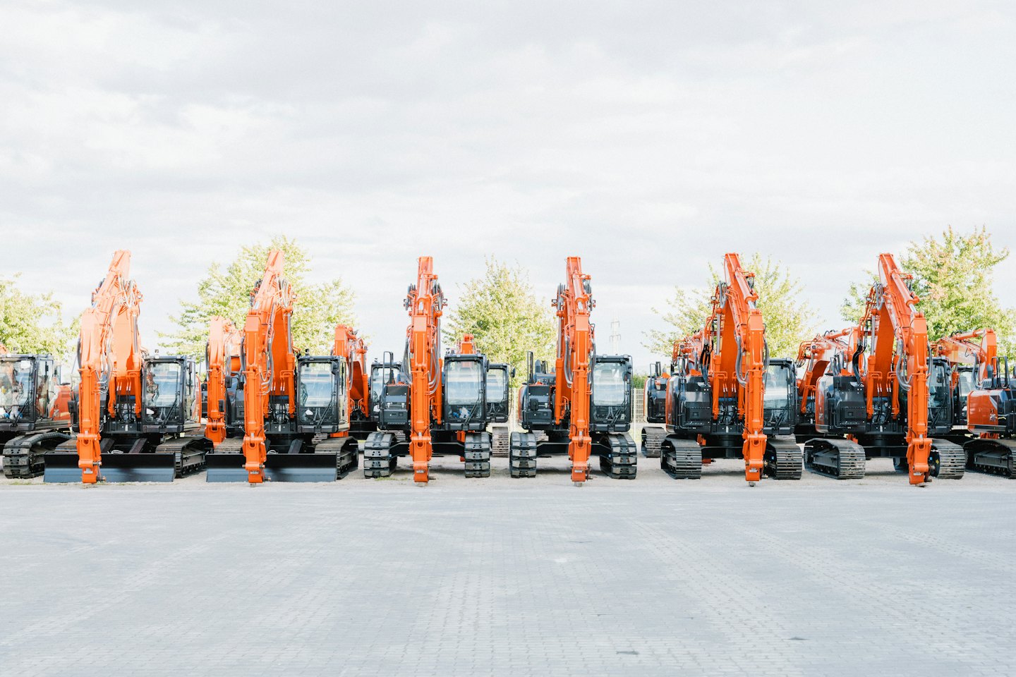 New orange and black excavators parked on a paved lot.