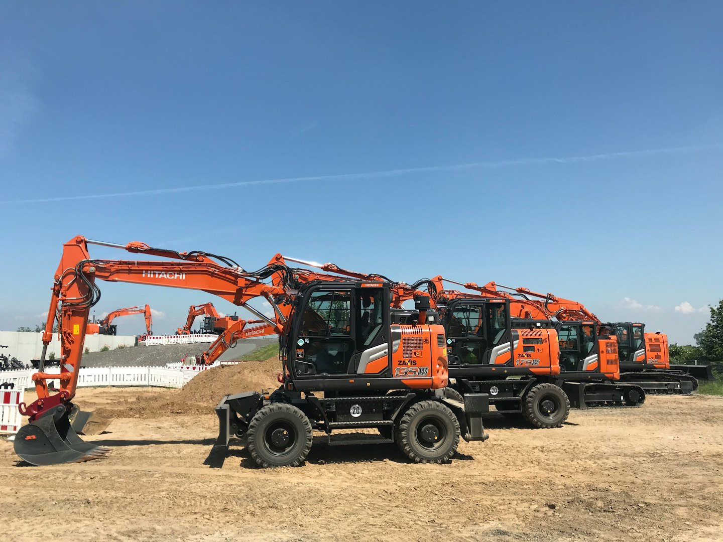 Orange and black excavators parked on a dirt construction site.