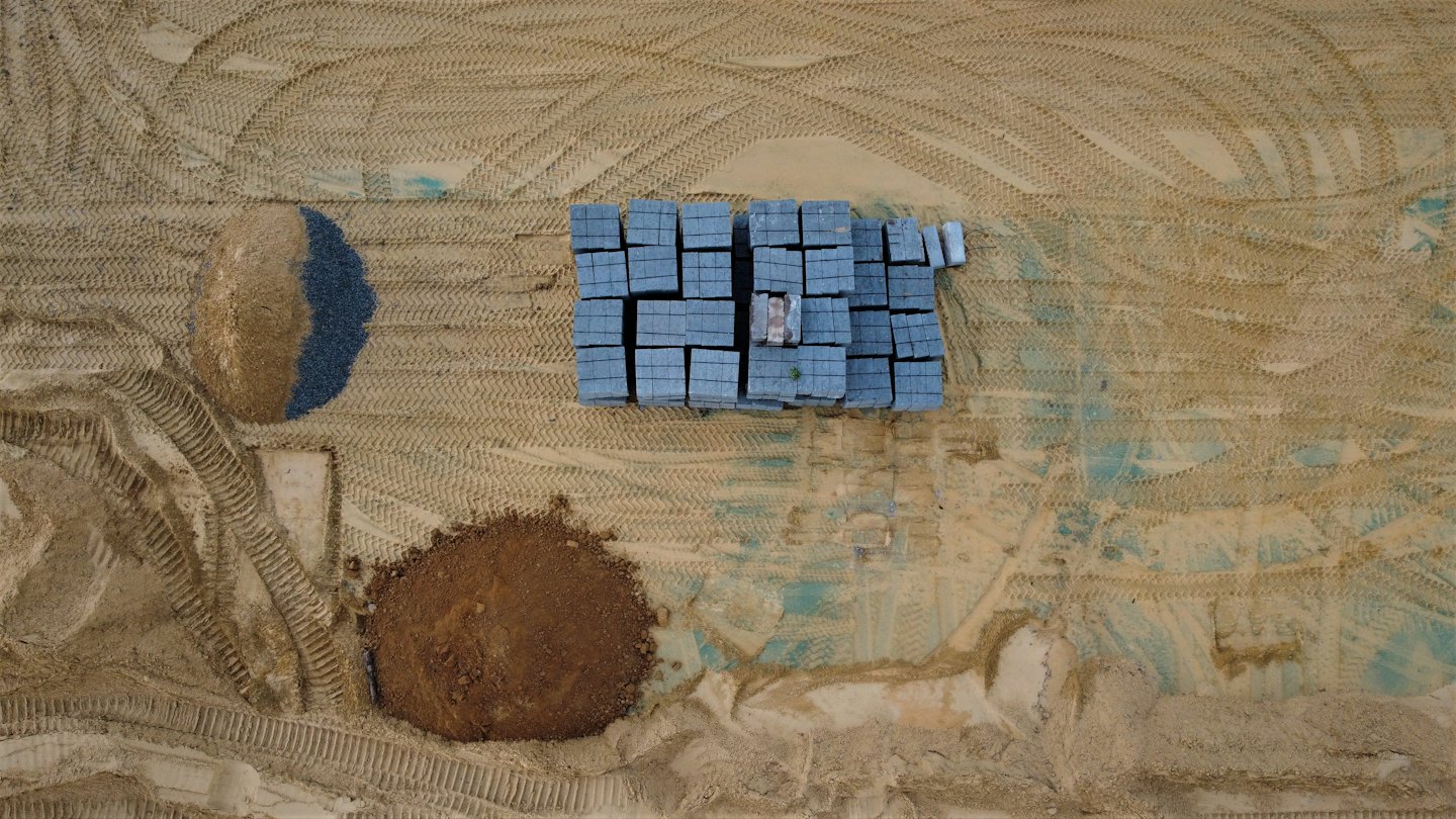 Stacks of paving stones and piles of gravel on construction site.