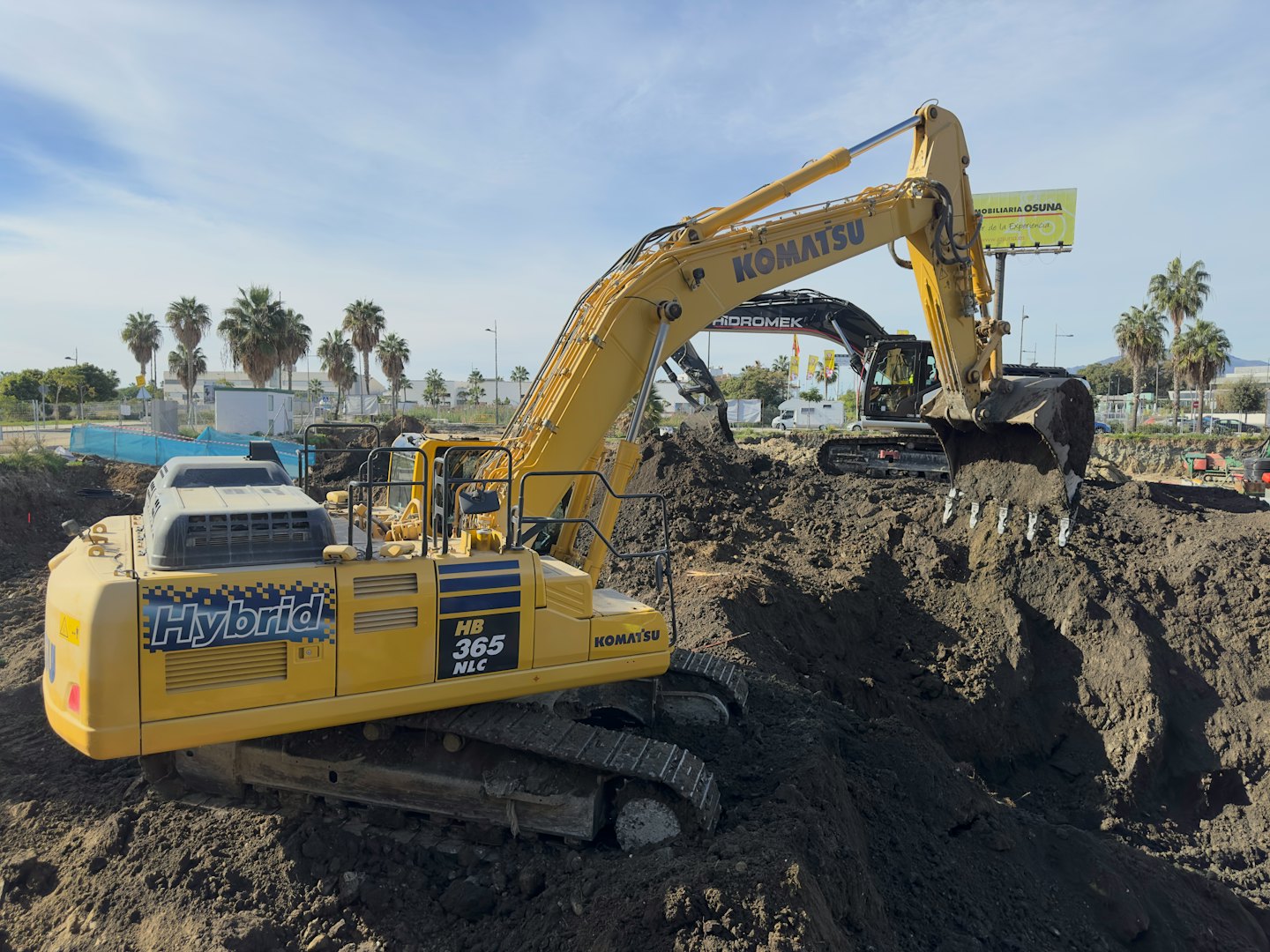 Two excavators working on a dirt construction site.